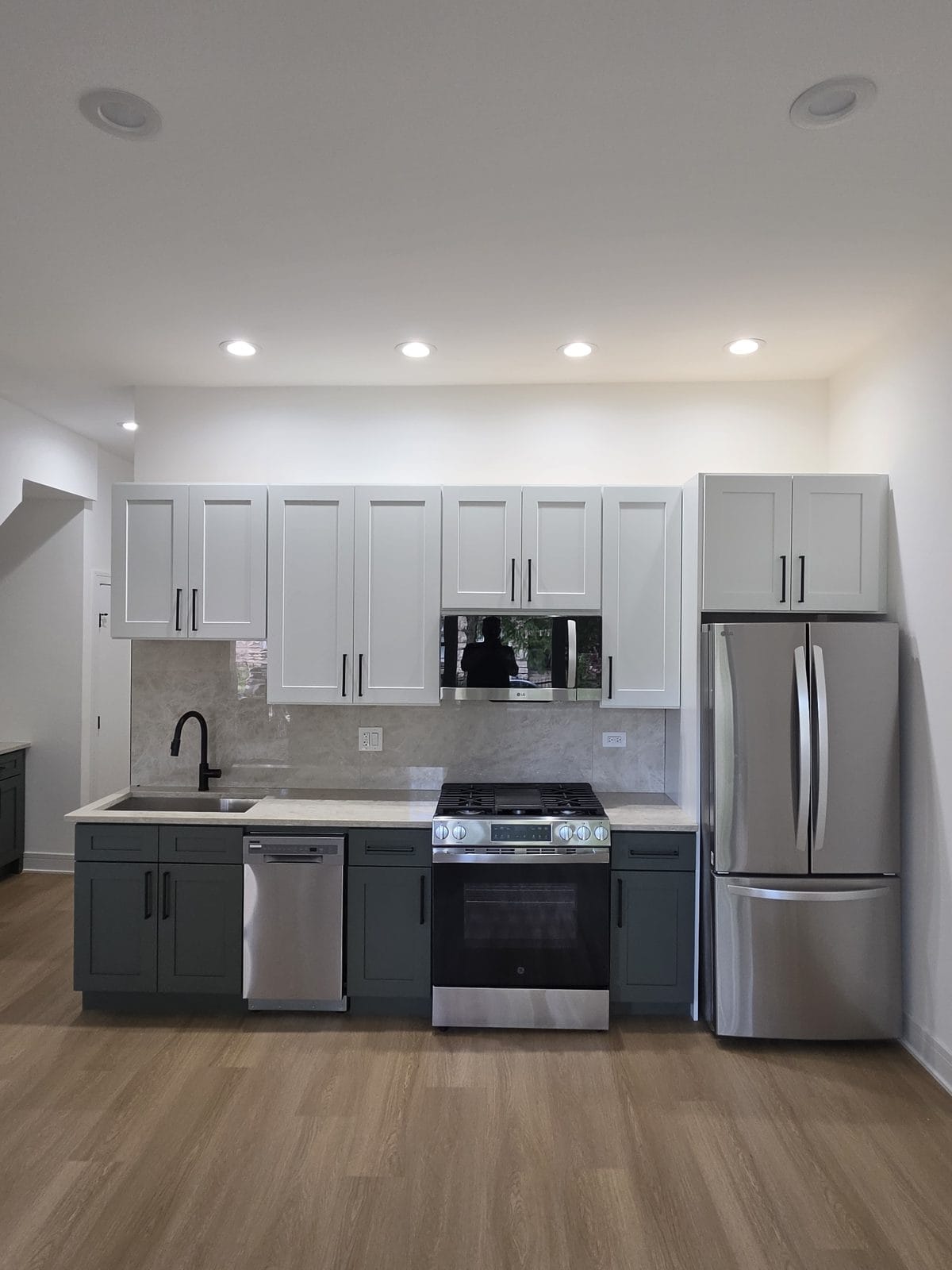 Sage green shaker kitchen cabinets with black hardware and quartz countertops in an Englewood, Chicago home