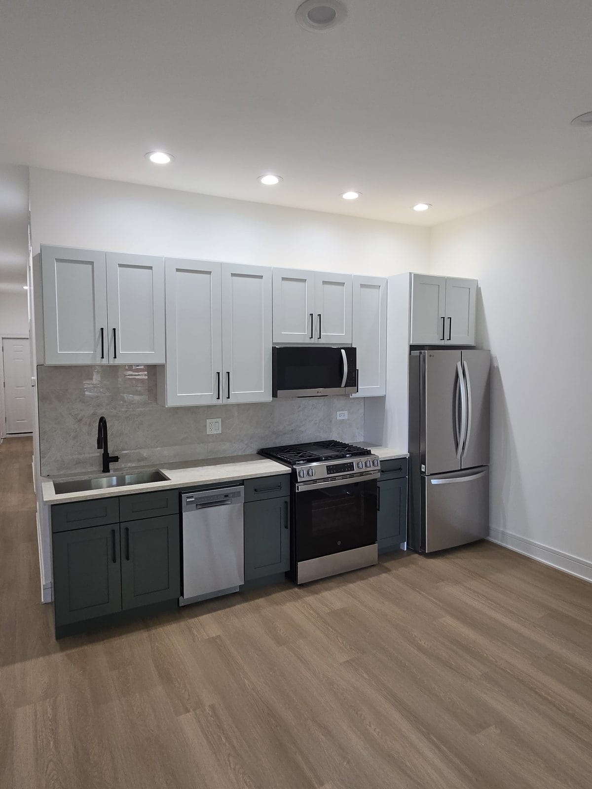 Sage green shaker kitchen cabinets with black hardware and quartz countertops in an Englewood, Chicago home