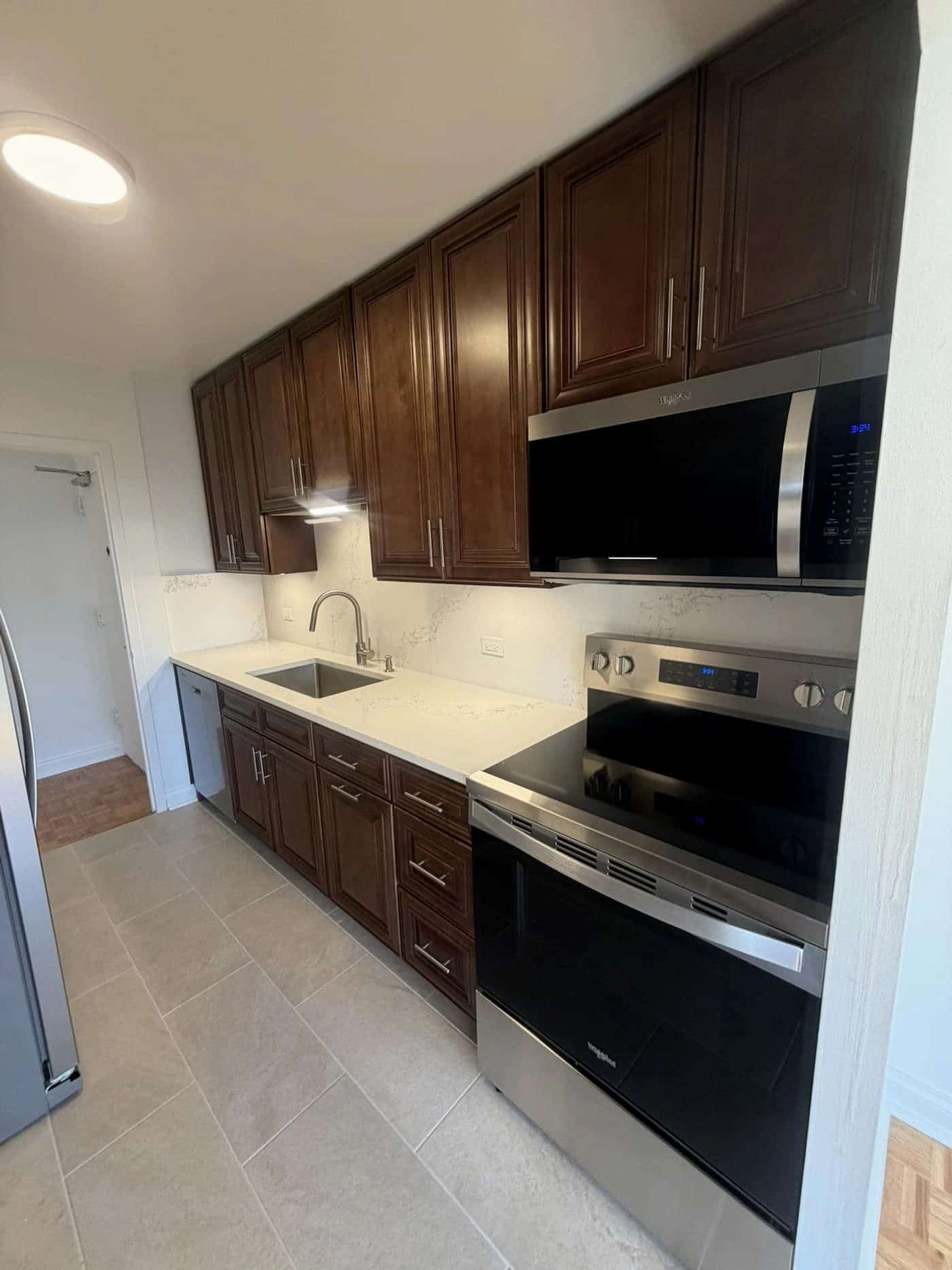 Charleston Saddle cabinets showing fridge wall layout in Lakeview East condo kitchen.