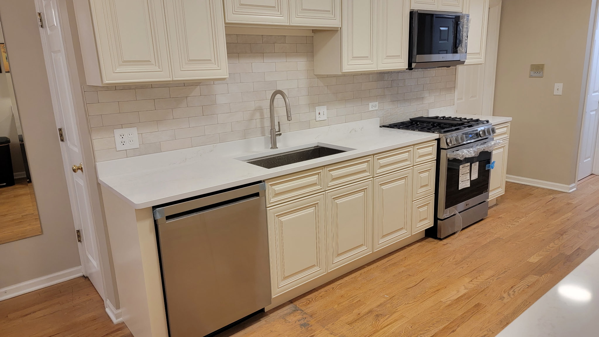 Charleston White base cabinets and drawers with a stainless dishwasher and red oak floors in a Lakeview, Chicago kitchen