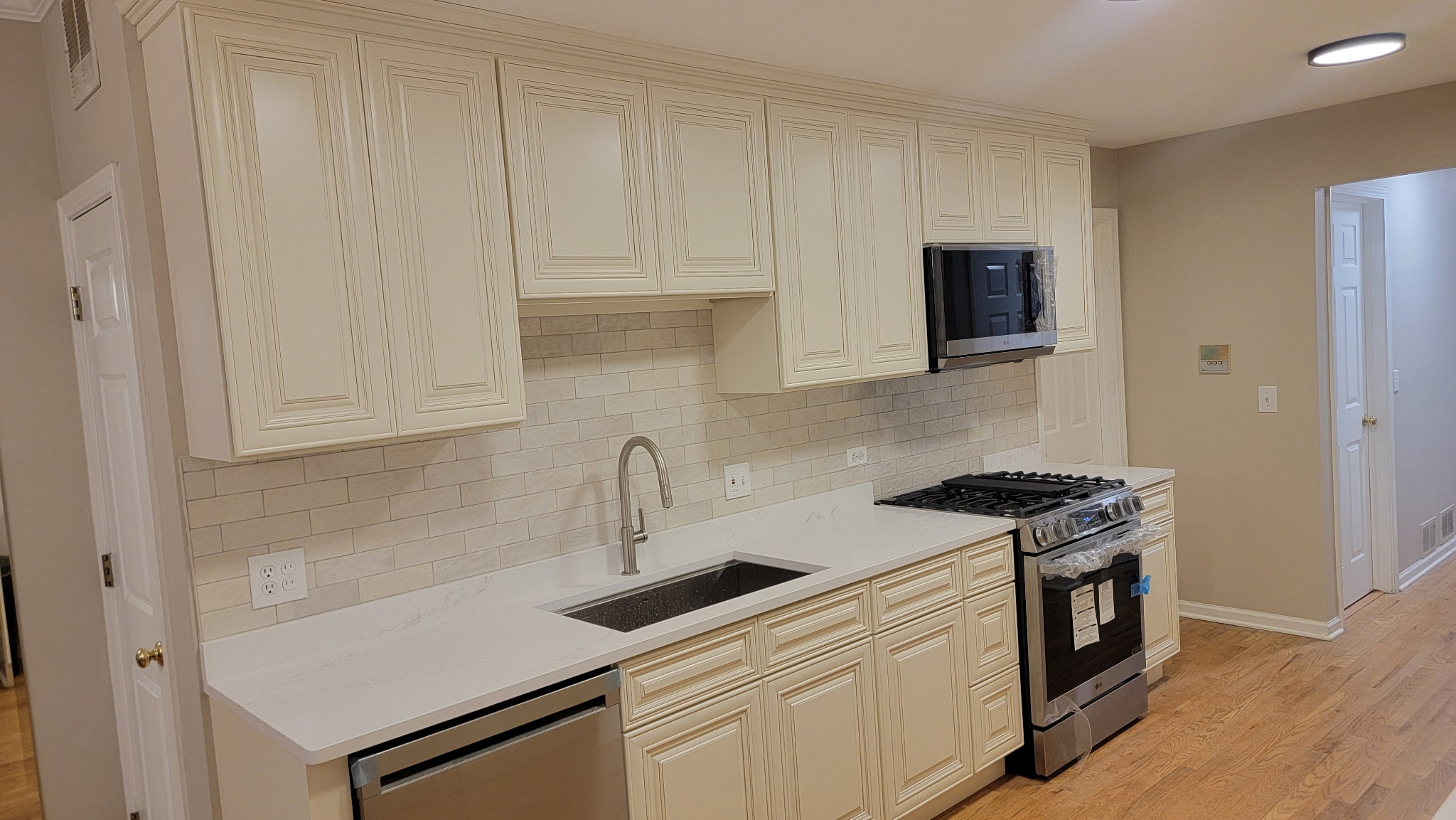 Charleston White raised-panel kitchen cabinets in a Lakeview, Chicago galley kitchen with white quartz counters and a taupe subway tile backsplash