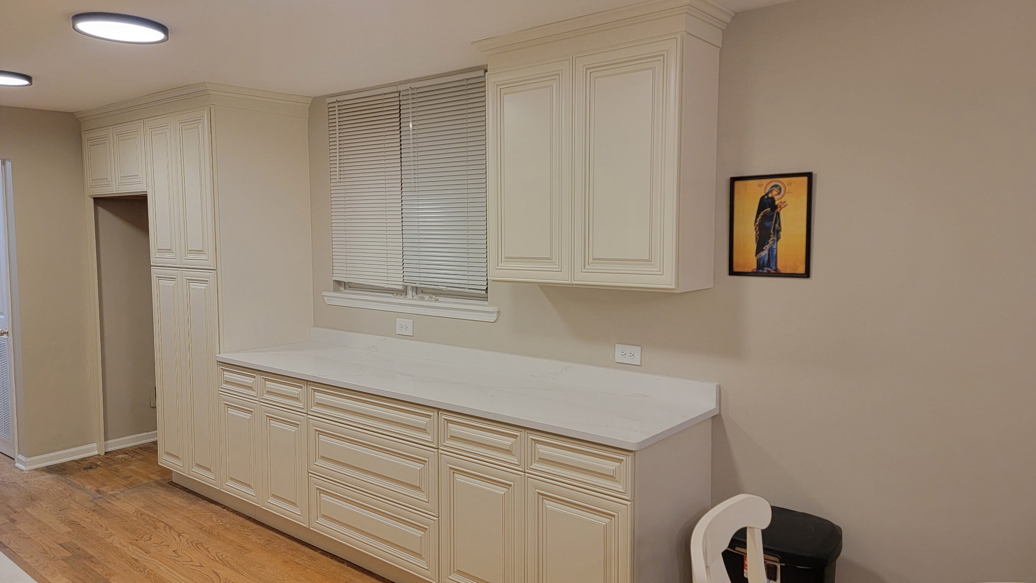 Tall Charleston White pantry cabinet and a run of base cabinets and drawers on the opposite wall of a Lakeview, Chicago galley kitchen