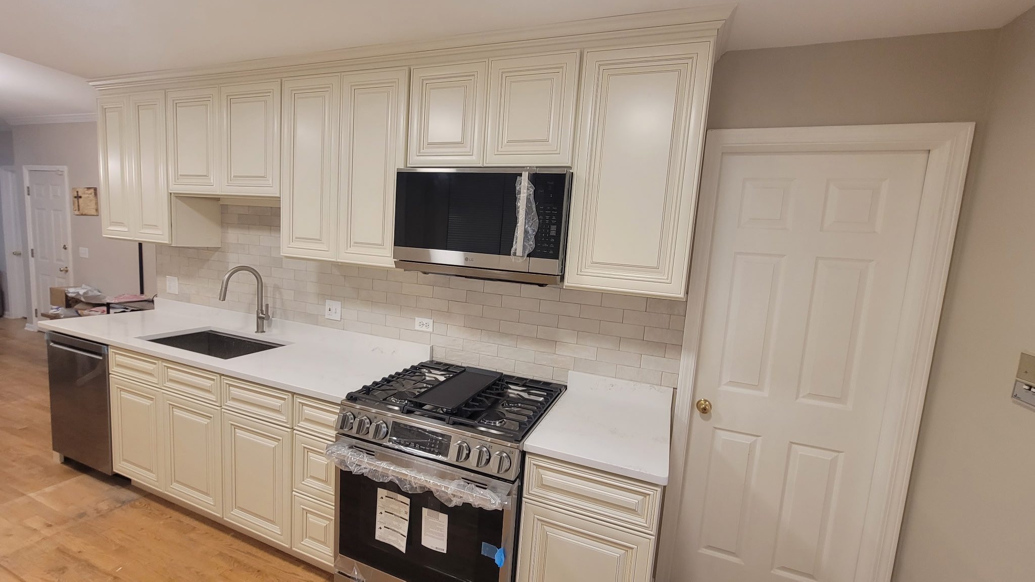 Charleston White cabinets along the range wall of a Lakeview kitchen with a stainless gas range, over-the-range microwave and crown moulding