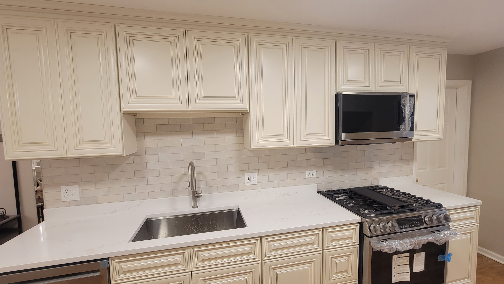 Undermount stainless sink and brushed-nickel pull-down faucet below Charleston White upper cabinets in a Lakeview, Chicago kitchen