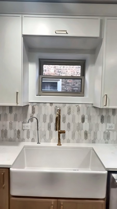 Dove White slim shaker upper cabinets, 42 inches tall, framing a lift-up cabinet above the window over a farmhouse sink in a Chicago kitchen.