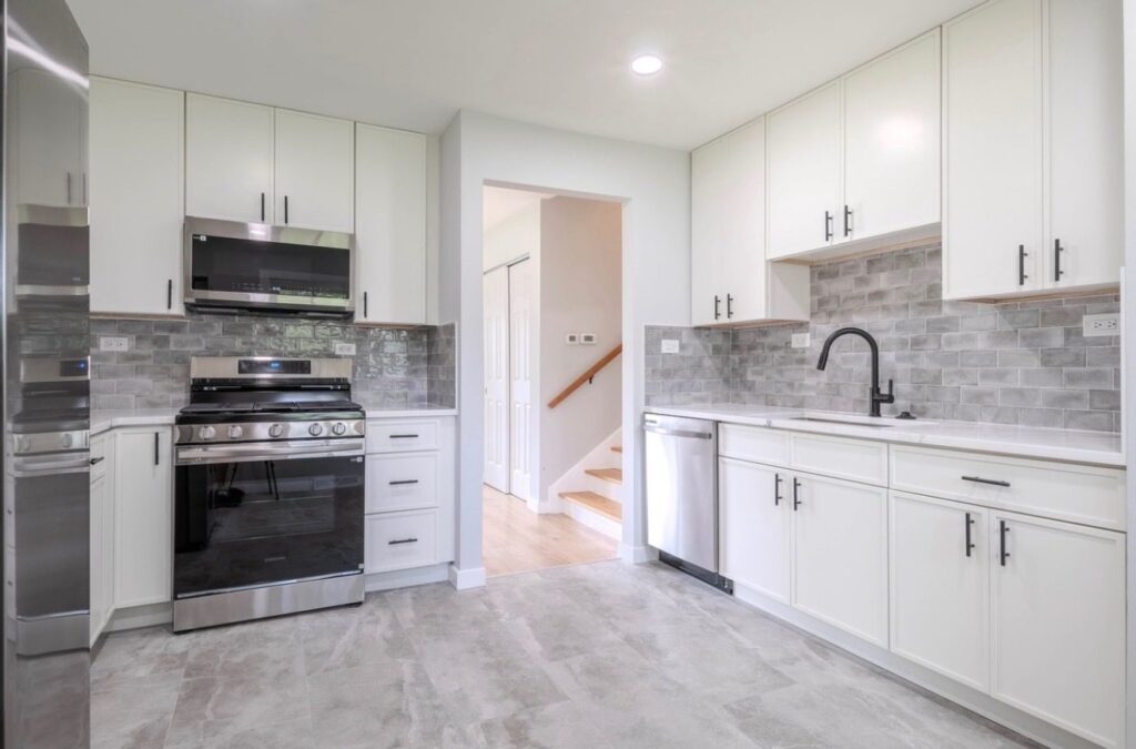 Timeless Shaker White kitchen cabinets with black bar pulls and a gray glazed subway tile backsplash in a rental unit, Dunning, Chicago