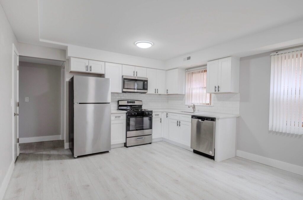 L-shaped Timeless Shaker White kitchen with white subway tile and stainless appliances in a rental unit, Dunning, Chicago