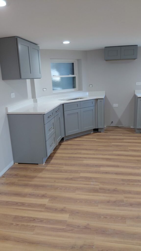Angled corner of gray shaker base cabinets under white quartz countertops, Humboldt Park, Chicago