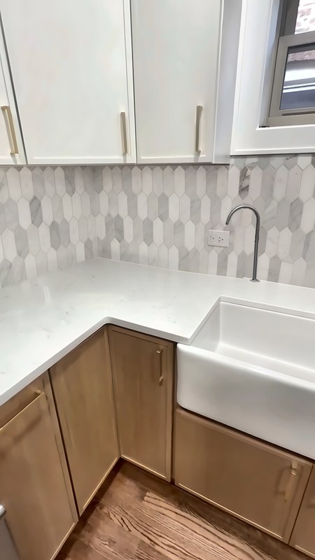 White-oak slim shaker corner base cabinet next to a 36-inch farmhouse sink base cabinet, with white quartz counters, in a Chicago kitchen.